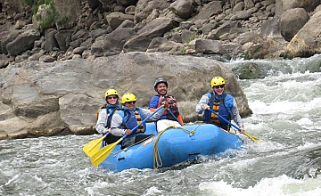 Rafting en Cusco: grupo en bote inflable con cascos en rápidos del rio